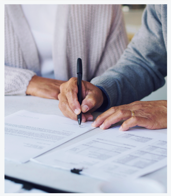 Cropped image showing hands carrying a black pen signing a contract with estate planning attorney